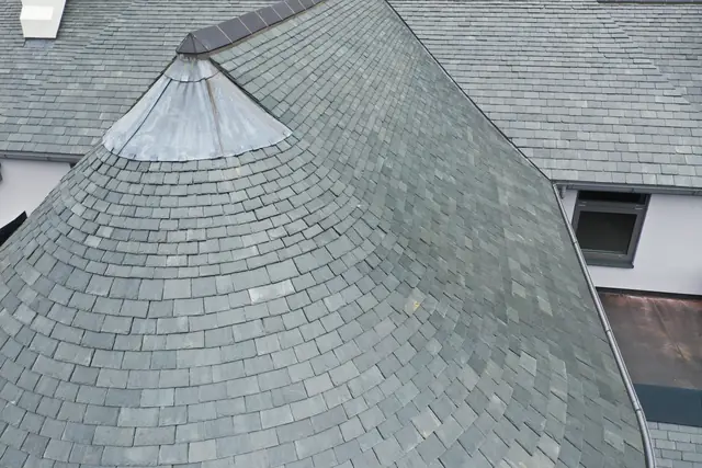 Natural slate laid in courses round a conical roof with a lead cone
