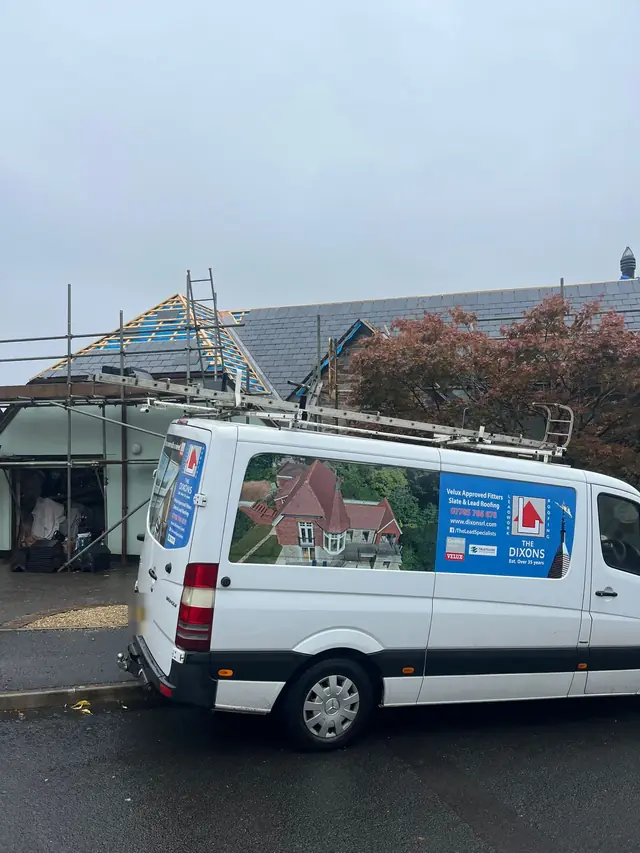 The Dixons van outside a slate re-roof in progress