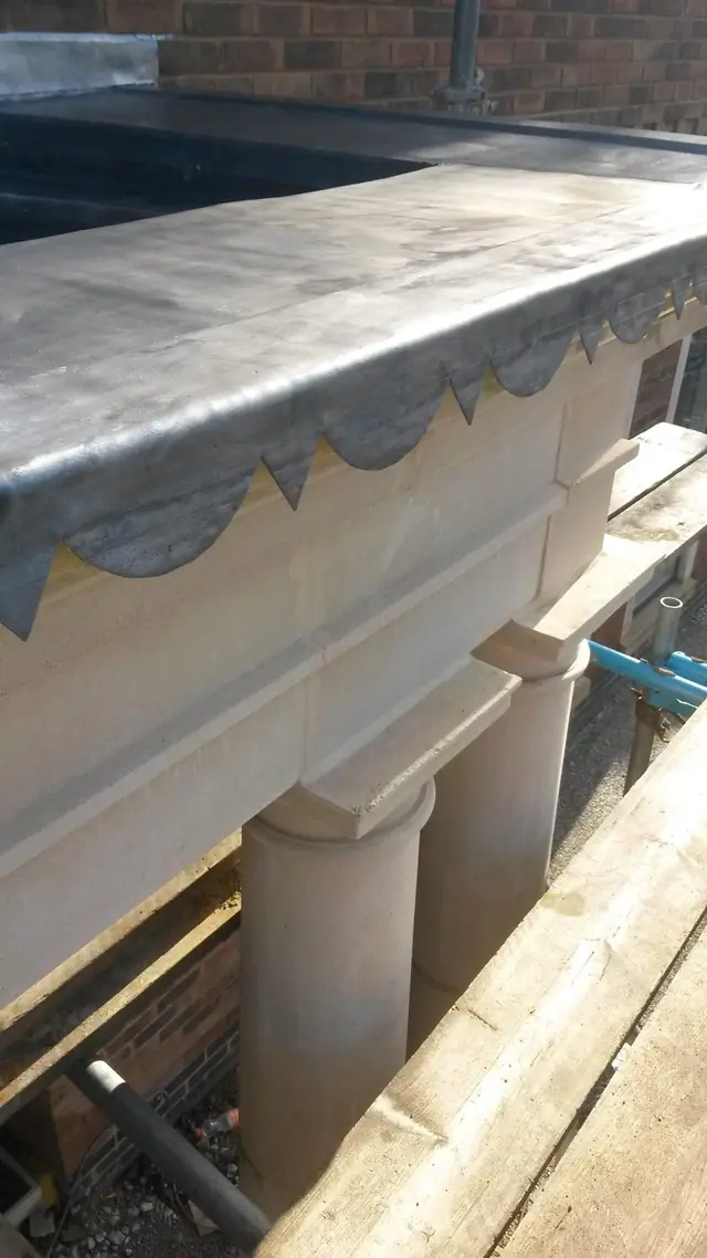 Lead roof with a decorative scalloped edge over a stone portico