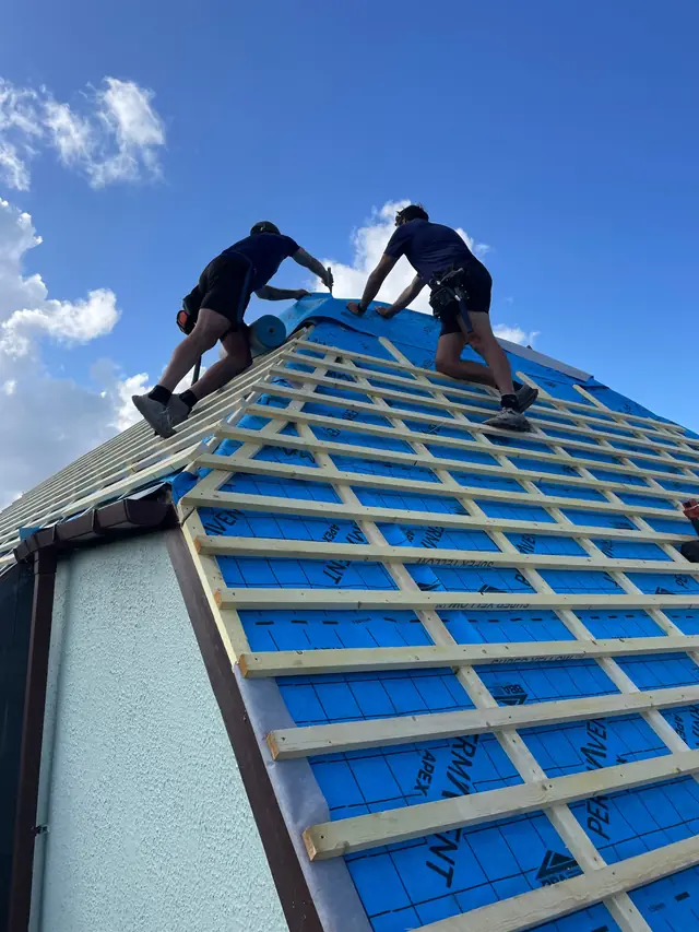 Two roofers fixing new battens over breathable membrane