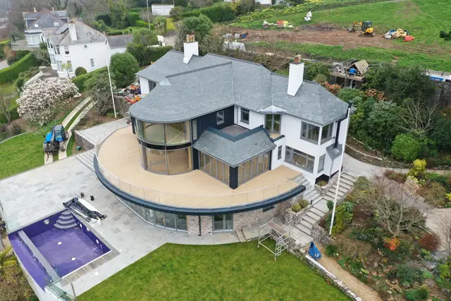 Drone view of a large house re-roofed in natural slate, with a curved slate roof