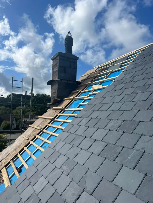 New natural slate roof beside a tall chimney stack