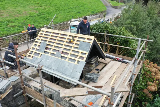 The team slating a small roof from the scaffold
