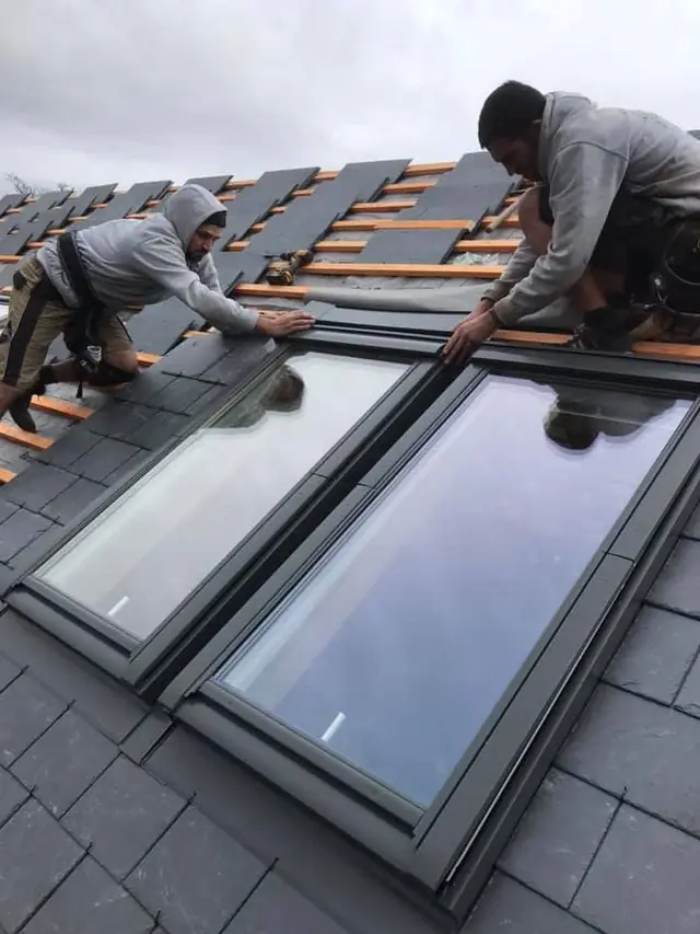 Two roofers slating around a new pair of VELUX roof windows