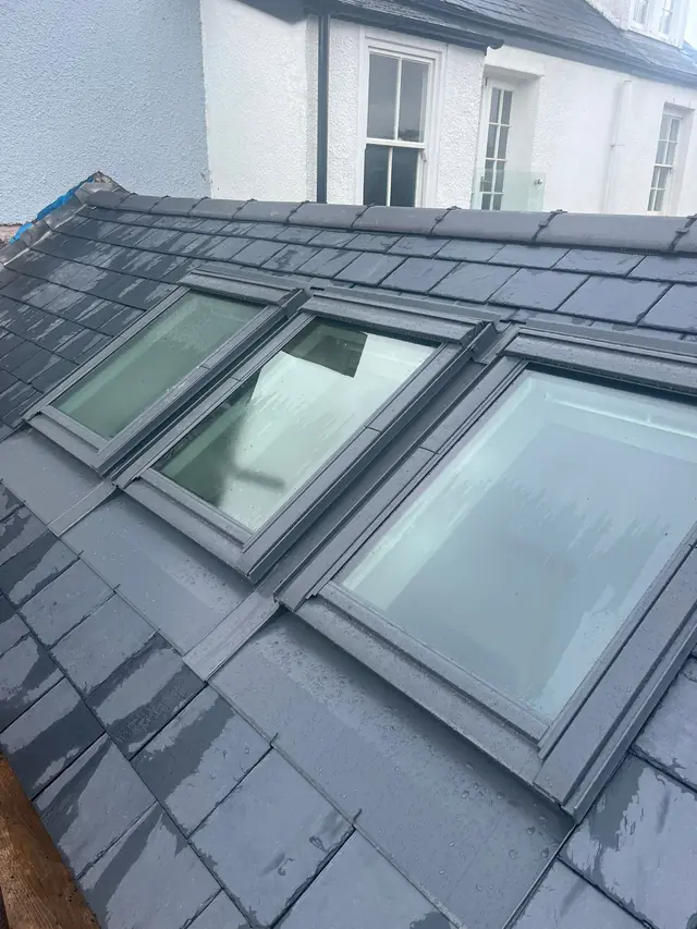 Three VELUX roof windows with matching grey flashings in a new slate roof